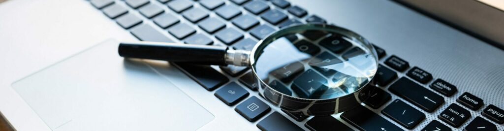 SEO news recap - Magnifying glass sitting on top of computer keyboard.